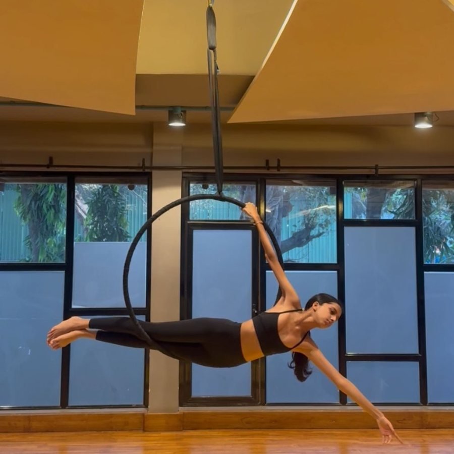 Ariana Shah suspended horizontally from an aerial hoop in a dance studio