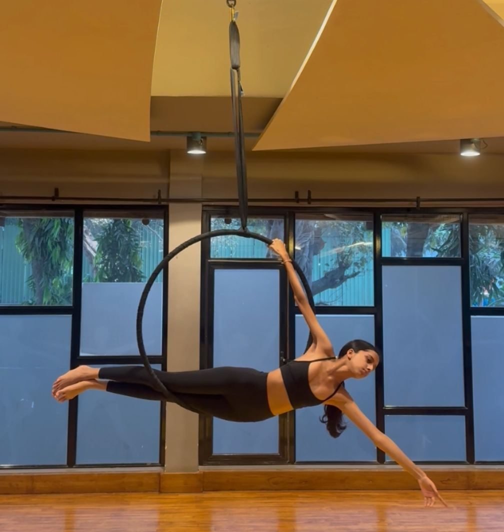 Ariana holding a horizontal pose on an aerial hoop