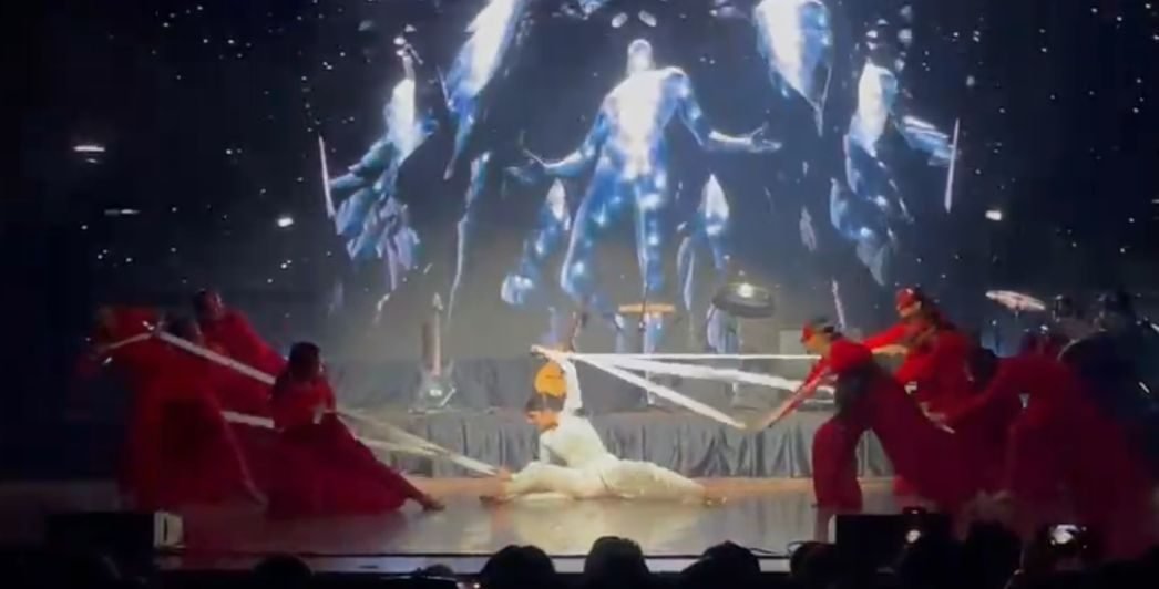 Performers in red costumes on a dramatically lit stage