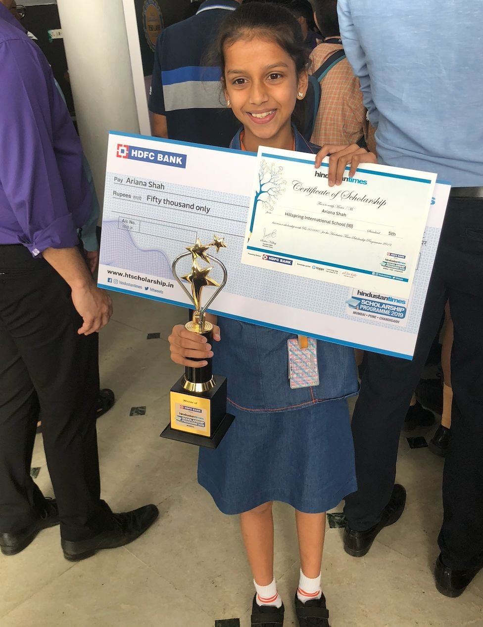 Ariana, aged eleven, holding an oversized cheque, certificate and trophy