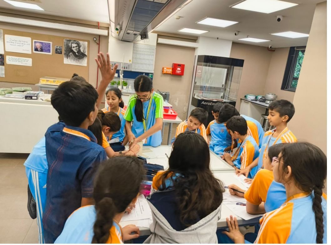 Students crowded around a table working on an activity while Ariana guides them